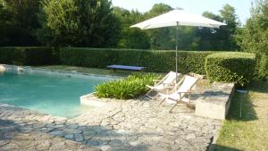 un par de sillas y una sombrilla junto a una piscina en Casale Oliva in a landscape of oaks, olive e cherry trees, en Santa Vittoria in Matenano