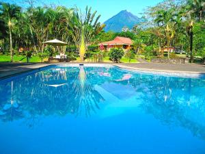 Una piscina azul con una montaña al fondo en Hotel Arenal Country Inn, en Fortuna