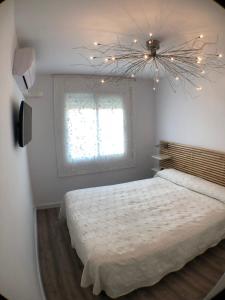 1 dormitorio con 1 cama con lámpara de araña y ventana en Don Ernesto, en Castelldefels