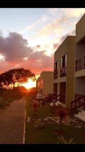 Flat condomínio paraíso serra negra في بيزيروس: مبنى مع غروب الشمس في الخلفية