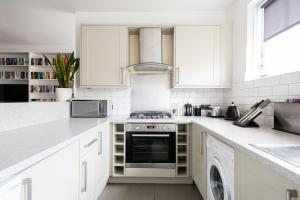 a kitchen with white cabinets and a stove top oven at The Paddington Mews - Comfortable & Elegant 3BDR Paddington Mews in London