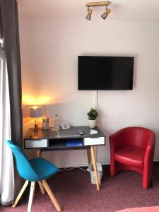 een kamer met een bureau, een stoel en een televisie bij Hotel Annablick in Strausberg