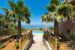 a resort with two palm trees and a swimming pool at Maroulas Villas Ioanna & Stavros, stunning views, By ThinkVilla in Maroulás