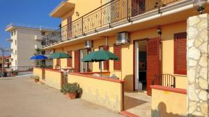 a building with tables and umbrellas in front of it at case vacanze piccolo in Balestrate