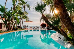 a swimming pool with palm trees and the ocean at Villa Do Mar in Arco da Calheta