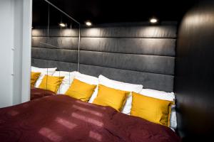 a bed with yellow pillows and a gray head board at Apartament Rynek22 in Kazimierz Dolny