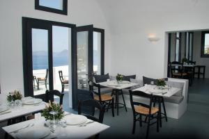 アクロティリにあるAmbassador Aegean Luxury Hotel & Suitesの白いテーブルと椅子、窓のあるレストラン