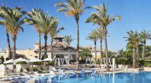 einen Pool in einem Resort mit Palmen und Stühlen in der Unterkunft Zeer trendy penthouse op de Mar Menor Golf & Padel Resort in Torre-Pacheco