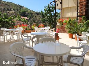 eine Gruppe von Tischen und weißen Stühlen auf einer Terrasse in der Unterkunft Ekali Hotel in Kakopetria