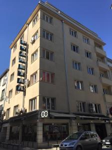 um edifício alto com um carro estacionado em frente em Rooftop Oscar Rooms em Sófia