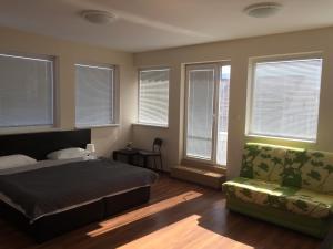um quarto com uma cama, um sofá e janelas em Rooftop Oscar Rooms em Sófia