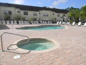a swimming pool in a brick courtyard with chairs and a building at Great Lovely Family Apartment close Disney in Kissimmee