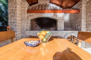 a wooden table with a bowl of fruit and a fireplace at Holiday House Lavanda in Vrsi