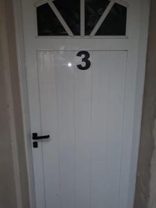 Una puerta blanca con el número tres. en Bungalow anita Nº 3 en Colón