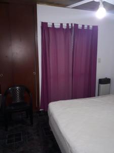 1 dormitorio con cama y cortina púrpura en Bungalow anita Nº 3 en Colón