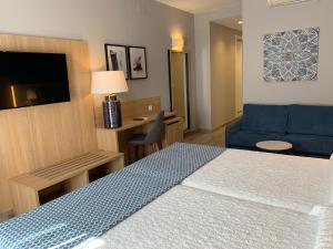 a hotel room with a bed and a blue couch at Hotel Puerta del Mar - Adults Recommended in Nerja
