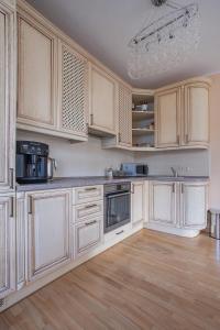 uma cozinha com armários brancos e pisos em madeira em Vilnius avenue apartments em Druskininkai