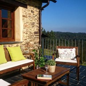 a patio with two chairs and a table on a deck at Casa Carballeira in Villarfernando