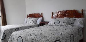 a bedroom with two beds with a comforter and pillows at Hotel Posada Sernichari in Cuetzalán del Progreso