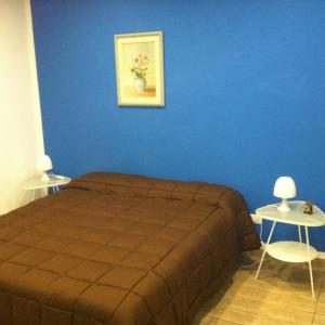 a bedroom with a blue wall with a bed and two tables at Casa Vacanze Mari in San Vito lo Capo