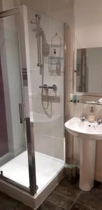 La salle de bains est pourvue d'une douche et d'un lavabo. dans l'établissement Sleep, Eat, Repeat Bed and Breakfast, à Macclesfield
