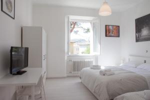 a white bedroom with two beds and a desk with a television at Cleo Giglio in Ancona