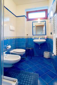a blue tiled bathroom with two sinks and a mirror at Il Glicine in Cetara
