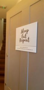 una señal en una puerta que lee sueño come repite en Sleep, Eat, Repeat Bed and Breakfast, en Macclesfield