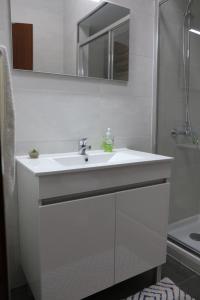 a white bathroom with a sink and a mirror at Apartamento Tres Marias in Lagoa