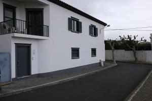 a white house with black windows and a driveway at Apartamento Tres Marias in Lagoa