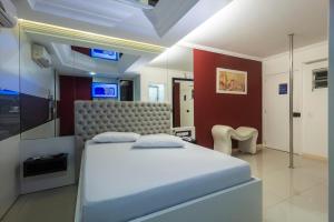 Un dormitorio con una cama blanca y una silla. en Motel 2001 (Adults Only), en São José