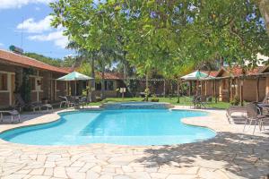 a swimming pool in a yard with chairs and umbrellas at Pousada Faruk in Olímpia