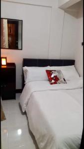 una camera con un letto bianco e un cuscino rosso di Estien's cozy home a Malagasang Primero