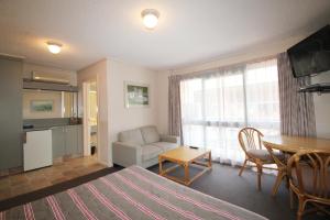 a room with a bed and a table and a couch at Beaumaris Bay Motel in Beaumaris