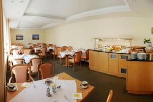 a dining room with tables and chairs and a kitchen at Wehrmann-Blume in Wunstorf