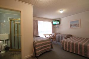 um quarto de hotel com duas camas e uma mesa em Beaumaris Bay Motel em Beaumaris