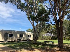 a building with tables and an umbrella in the grass at Peppermint Grove Beach Holiday Park in Capel