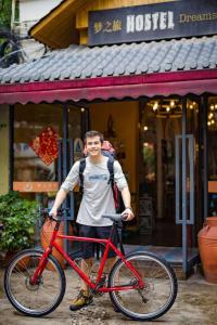 a man holding a red bike in front of a building at Chengdu Dreams Travel International Youth Hostel in Chengdu