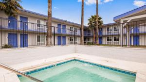 a swimming pool in front of a building with palm trees at SureStay Plus Hotel by Best Western Sacramento Cal Expo in Sacramento