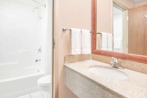 a bathroom with a sink and a toilet and a mirror at Baymont by Wyndham Springfield South Hwy 65 in Springfield