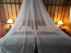 a bed with a mosquito net in a room with two lamps at Sandy Beach Bungalows in Gili Islands