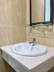 La salle de bains est pourvue d'un lavabo blanc et d'un miroir. dans l'établissement Hotel Lê My, à Cần Thơ