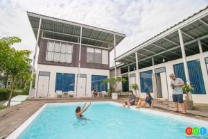 a group of people sitting around a swimming pool at Arthit -Tara Lodge in Prachin Buri