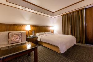a hotel room with a large bed and a table at Kingshi Hotel Taipei in Taipei