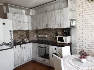 a kitchen with wooden cabinets and a table and a microwave at Kalina apartment in Ruse