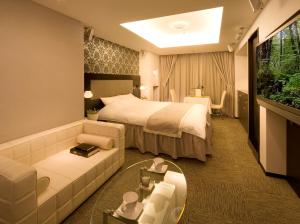 ein Hotelzimmer mit einem Bett und einer Couch in der Unterkunft Carrot ISE (Adult Only) in Ise