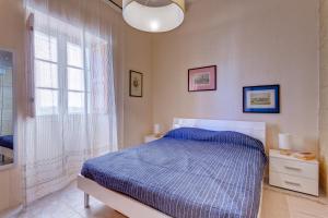 a bedroom with a blue bed and a window at Traditional Maltese Townhouse, Roof Terrace and Views in Senglea