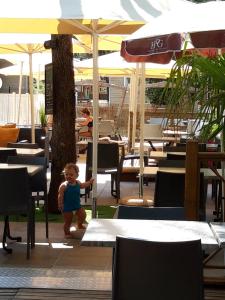 un bébé debout sous un parasol dans un restaurant dans l'établissement Mobil Home Sainte Baume, à Nans-les-Pins