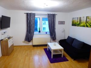 a living room with a black couch and a window at Ferienwohnung zum Pinguin in Wiednitz