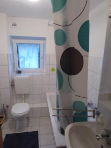 La salle de bains est pourvue de toilettes, d'un lavabo et d'une fenêtre. dans l'établissement Ferienwohnung zum Pinguin, à Wiednitz